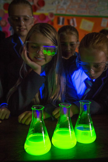 Pupils in science class watching illuminous chemicals